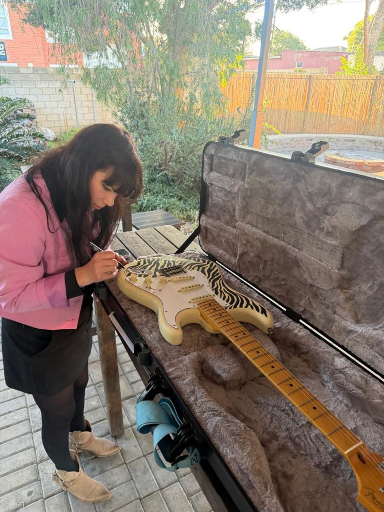 Hilde drawing a zebra pattern onto an electric guitar