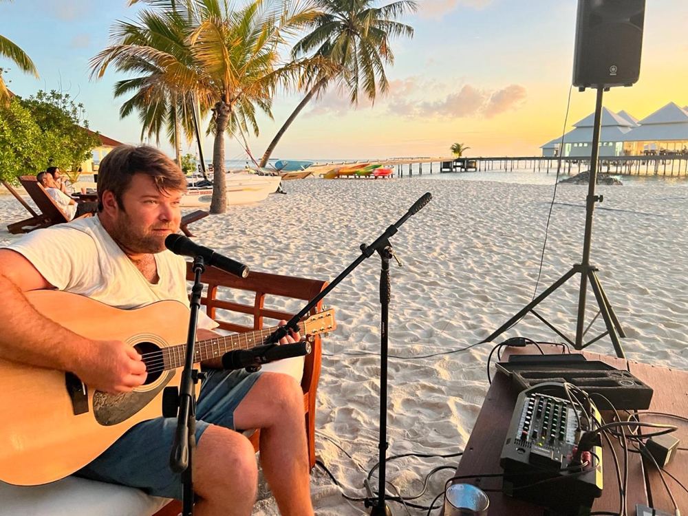 Jakoos Scheepers playing guitar and singing on the beach at Thudufushi at sunset