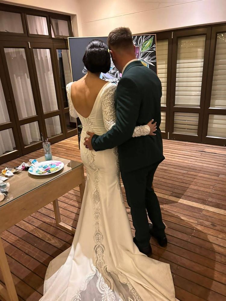 Bride and groom standing together in front of their finished painting