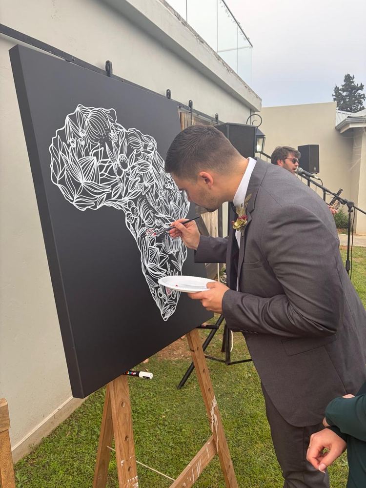 A wedding guest painting colour into an Africa floral artwork at Mooihoek