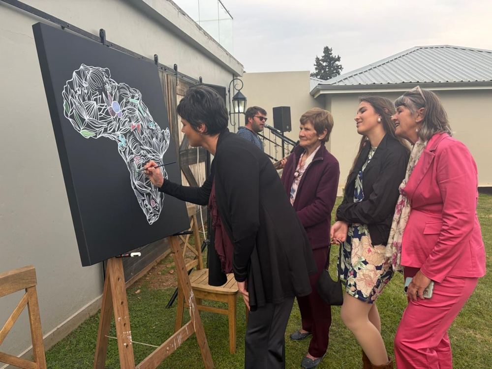Wedding guests colouring in an Africa floral artwork while Jakoos plays live music at Mooihoek
