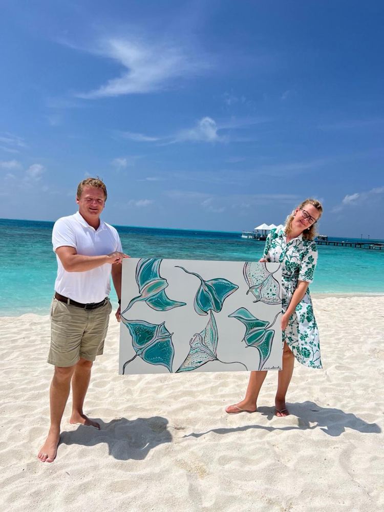 A turquoise manta ray artwork held up on the beach at Thudufushi